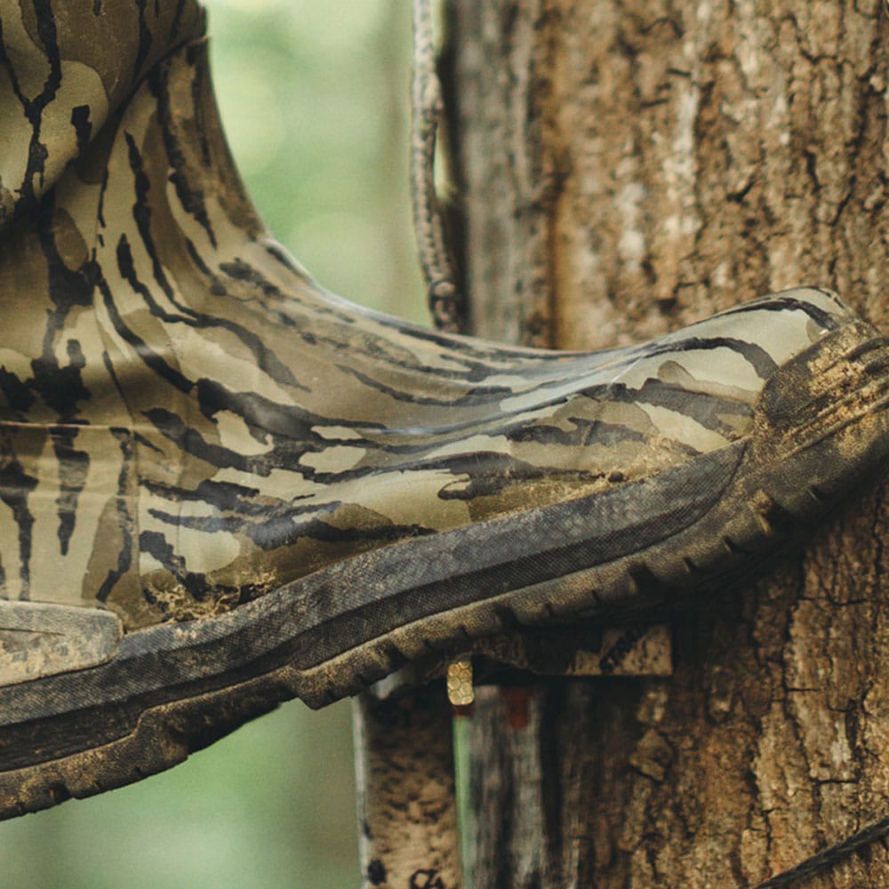 A camo boot ascending a tree to a hunting stand.