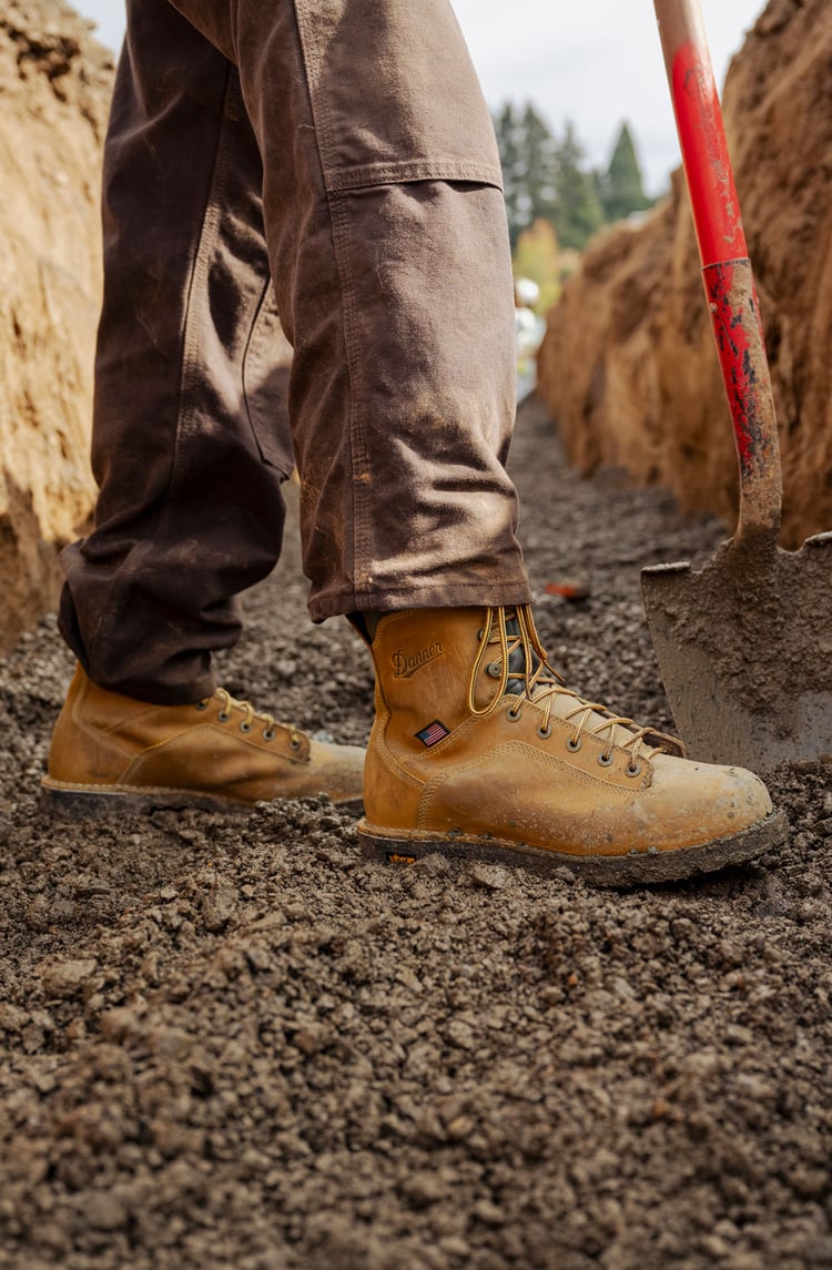 a man wearing heavy duty brown work boots while digging in a trench
