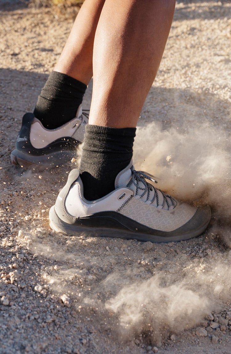 A pair of low cut hiking shoes kicks up dust along the trail