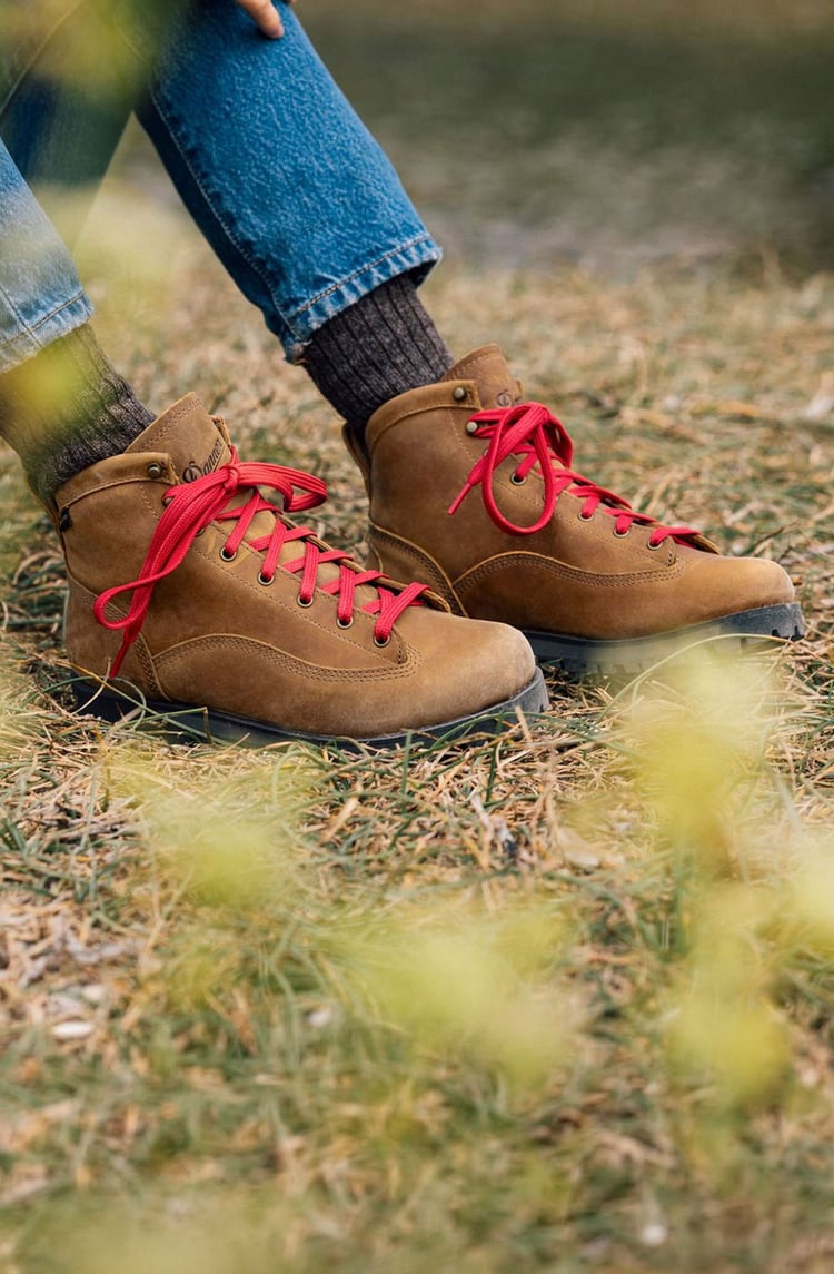 A man hiking through an open field with rocks in the background