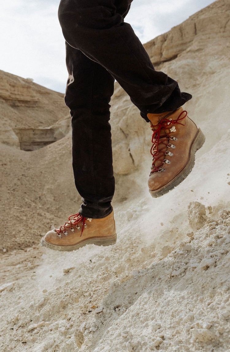 A man hiking through an open field with rocks in the background