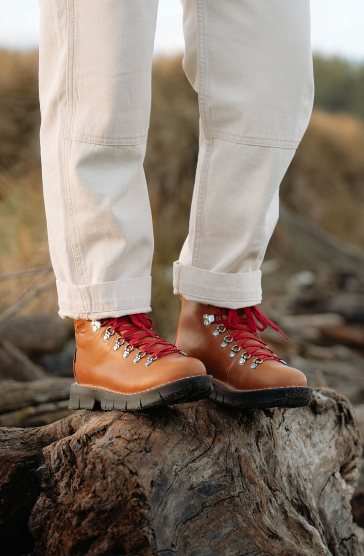 A man hiking through an open field with rocks in the background