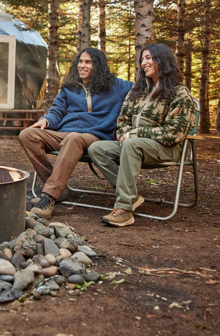 A man hiking through an open field with rocks in the background