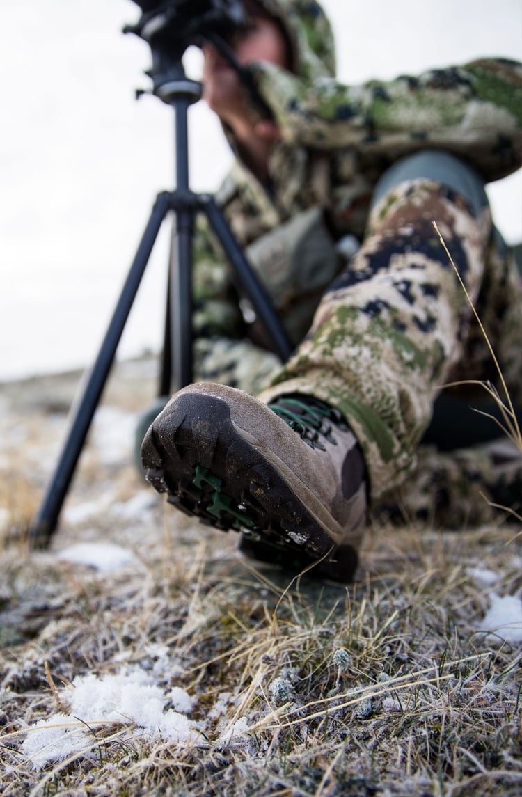 A woman hiking through an open field with rocks in the background