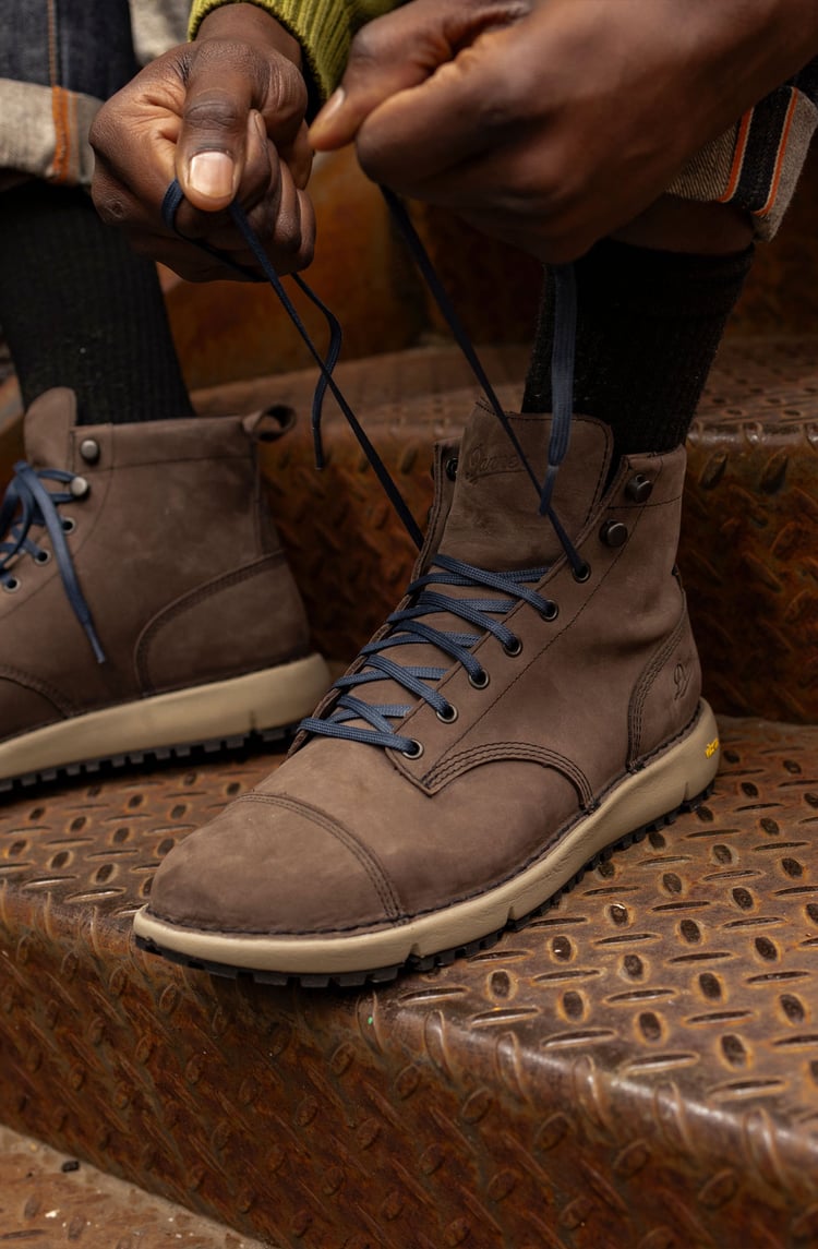 A man hiking through an open field with rocks in the background