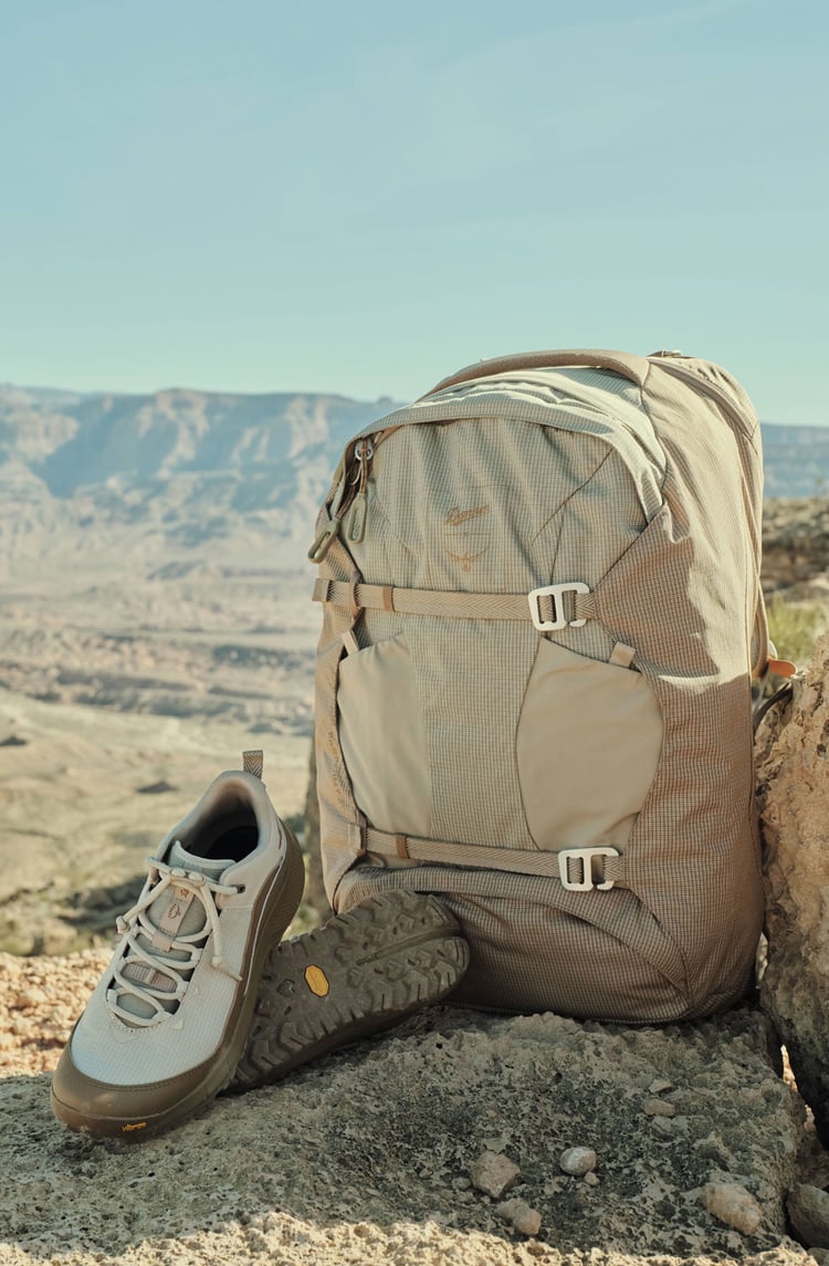 a pair of lightweight hiking boots sits next to an adventure ready backpack