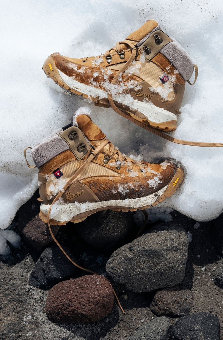 A man hiking through an open field with rocks in the background