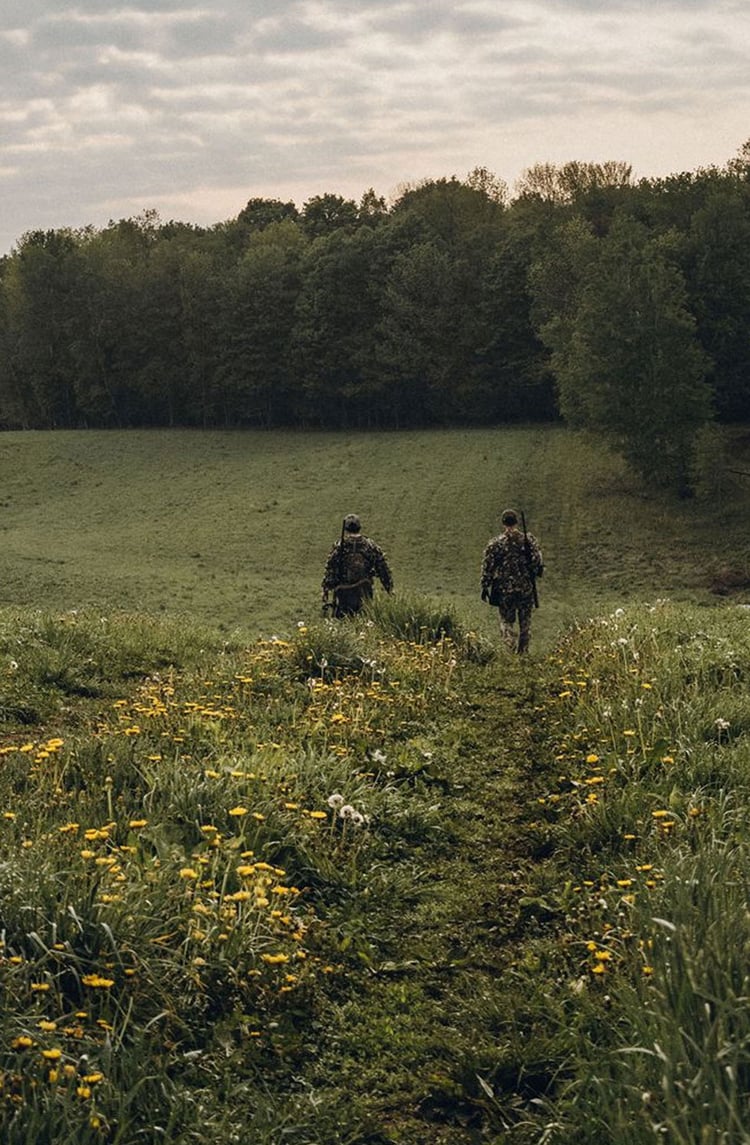 A man hiking through an open field with rocks in the background
