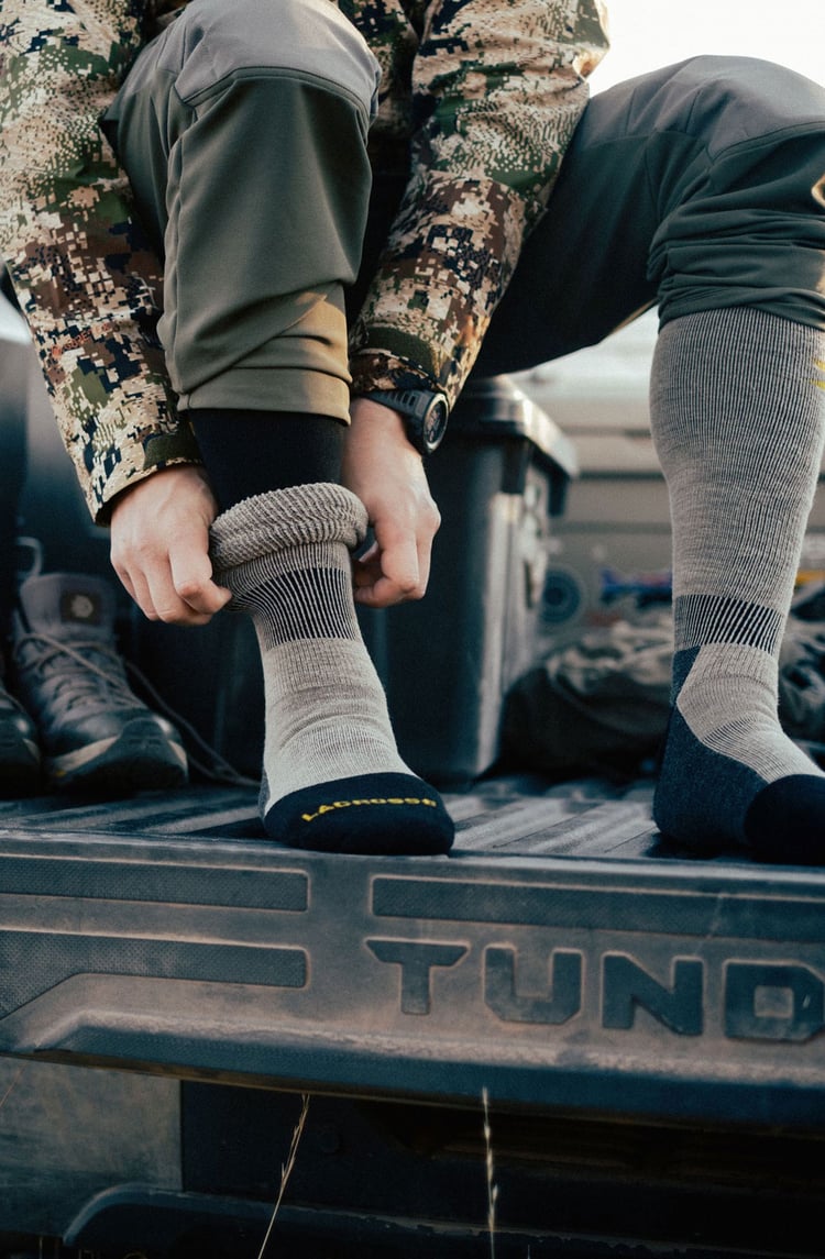 A man in gray boots ascending a tree