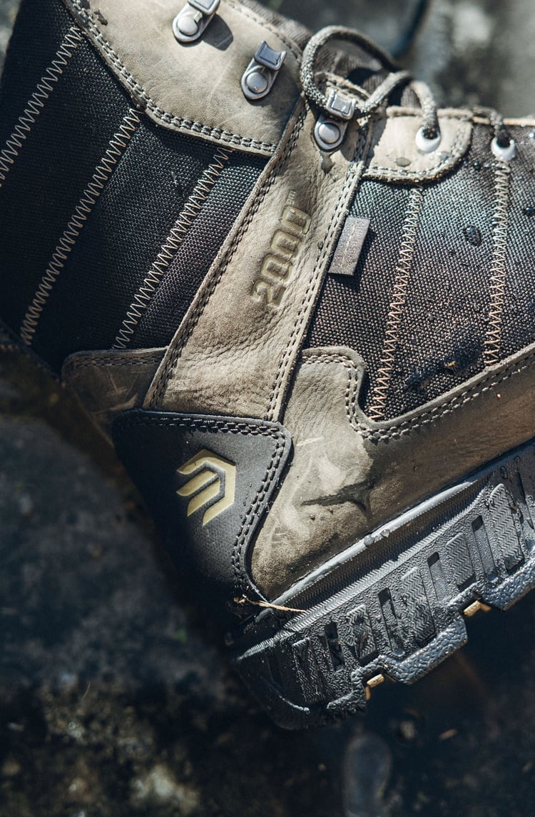 A man in gray boots ascending a tree