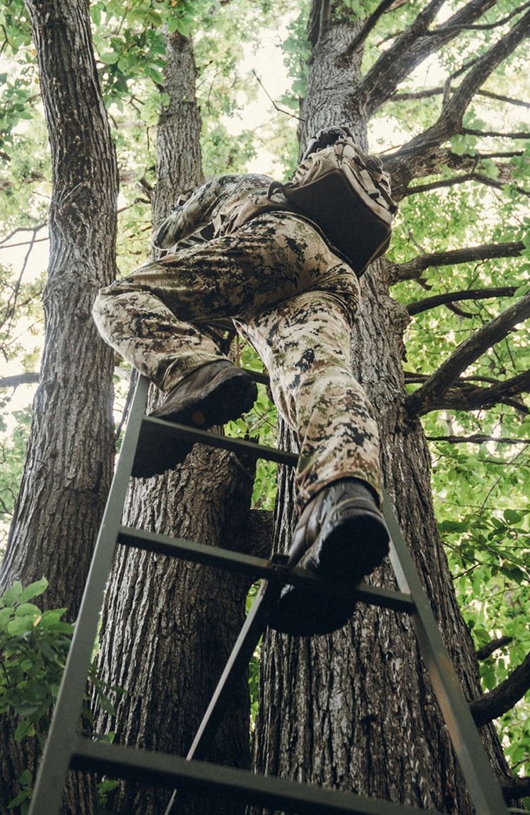 A man hiking through an open field with rocks in the background