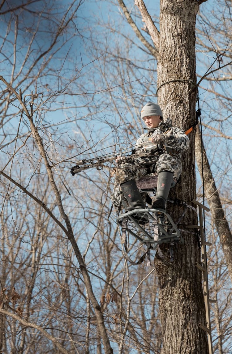 A man in gray boots ascending a tree