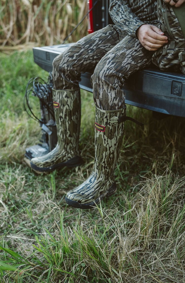 A man in gray boots ascending a tree