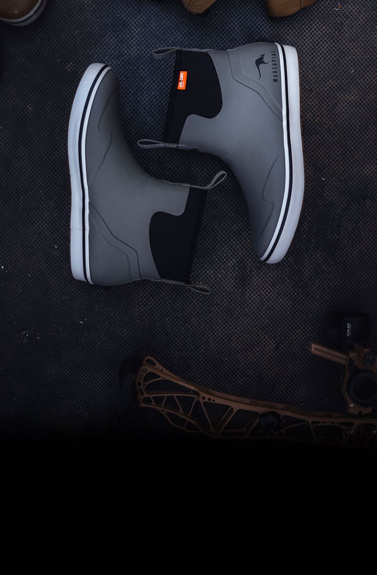 a pair of gray/green rubber boots against a dark background
