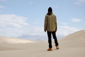 a pair of brown work boots with orange laces caked in mud