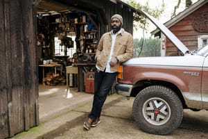 a pair of brown work boots with orange laces caked in mud