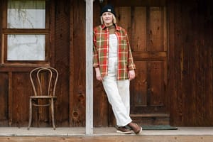 a man hikes against the backdrop of alpine lake wearing brown and red hiking boots