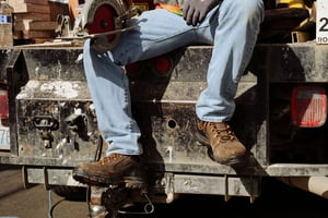 a man laces up a pair of brown suede boots