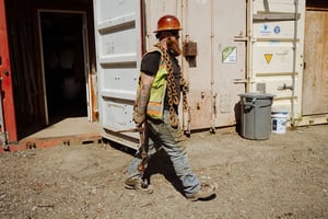 a pair of brown work boots with orange laces caked in mud