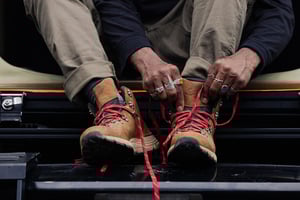 a man laces up a pair of brown suede boots