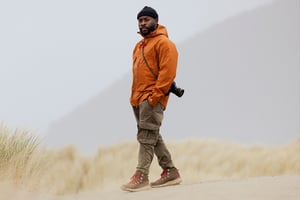 a pair of brown work boots with orange laces caked in mud