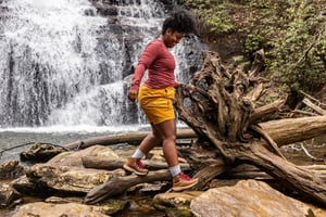 a man hikes against the backdrop of alpine lake wearing brown and red hiking boots