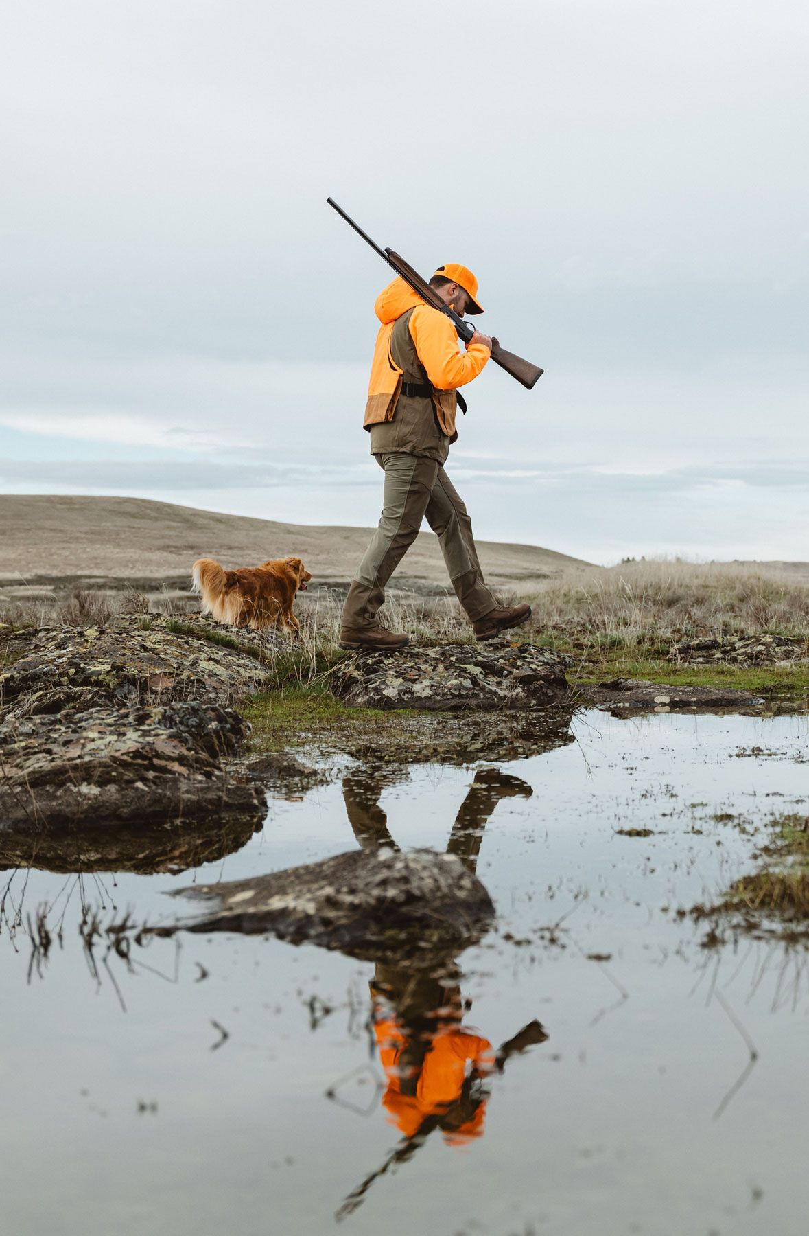A woman hiking through an open field with rocks in the background