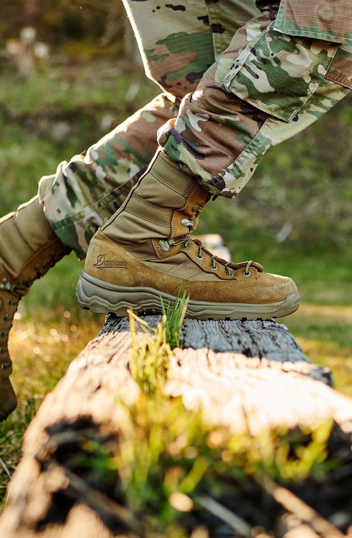 A man hiking through an open field with rocks in the background