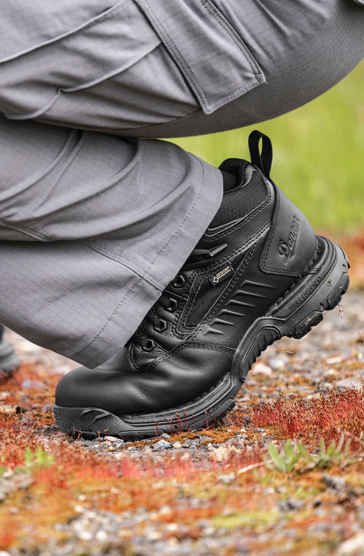A man hiking through an open field with rocks in the background