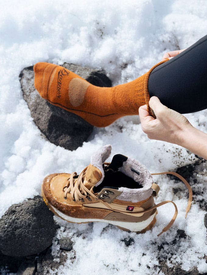 A stong-looking person suspends from a thick rope wearing camo pants, the rope is weaved around one foot showing the grippy outsole tread suggesting their boots are a key tool for their job