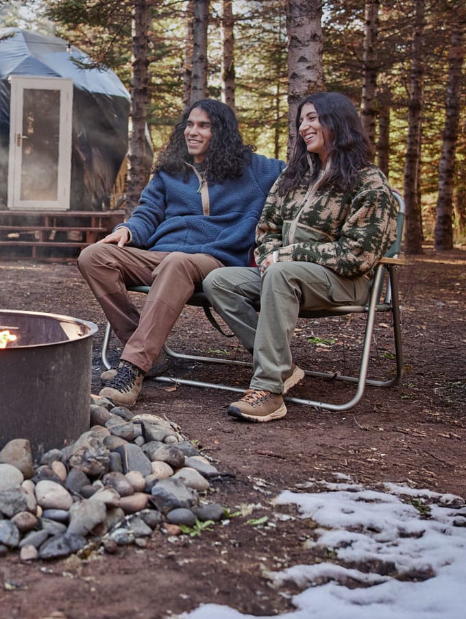 A hunter adorned in camo carries his rifle up a steep rocky hill