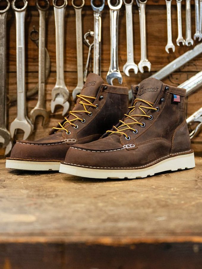 a worker climbs into a backhoe while wearing brown work boots