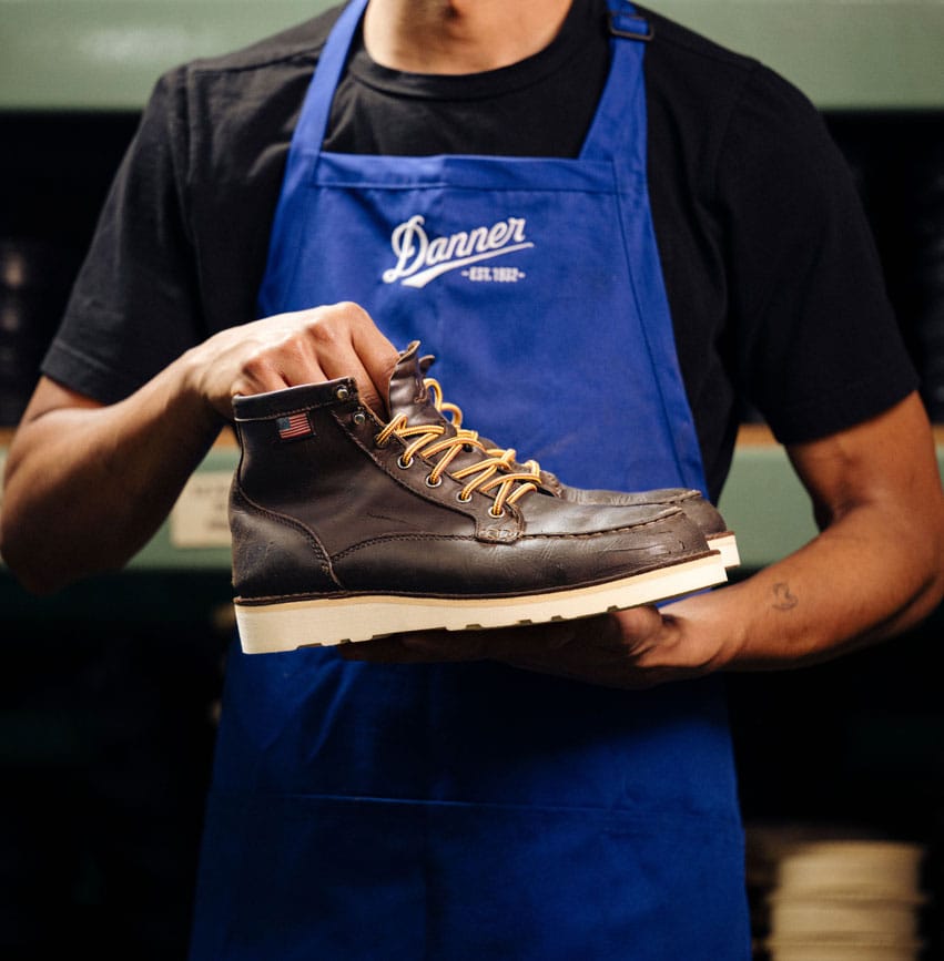 A man is using a computer to design a pair of Danner Boots.