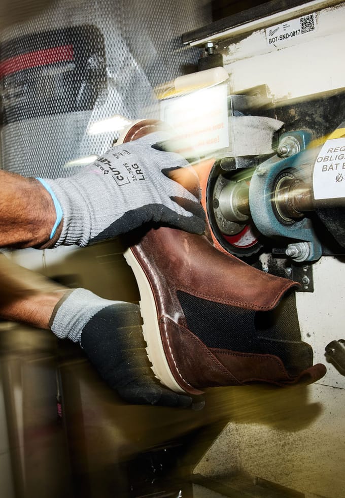 grinding the excess outsole away from a pair of brown boots