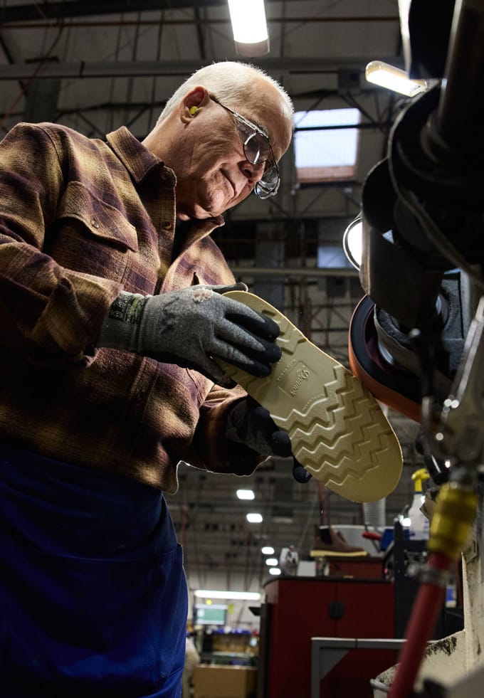grinding the excess outsole away from a pair of brown boots