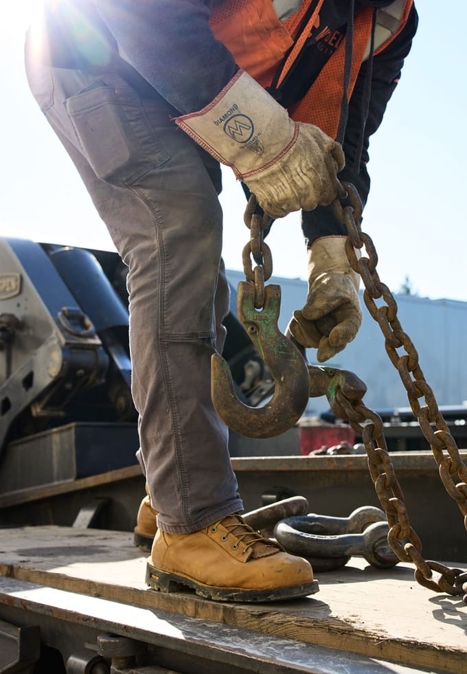 a man in brown work boots picking up a chain
