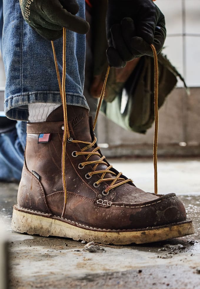lacing up a pair of brown work boots with a moc toe