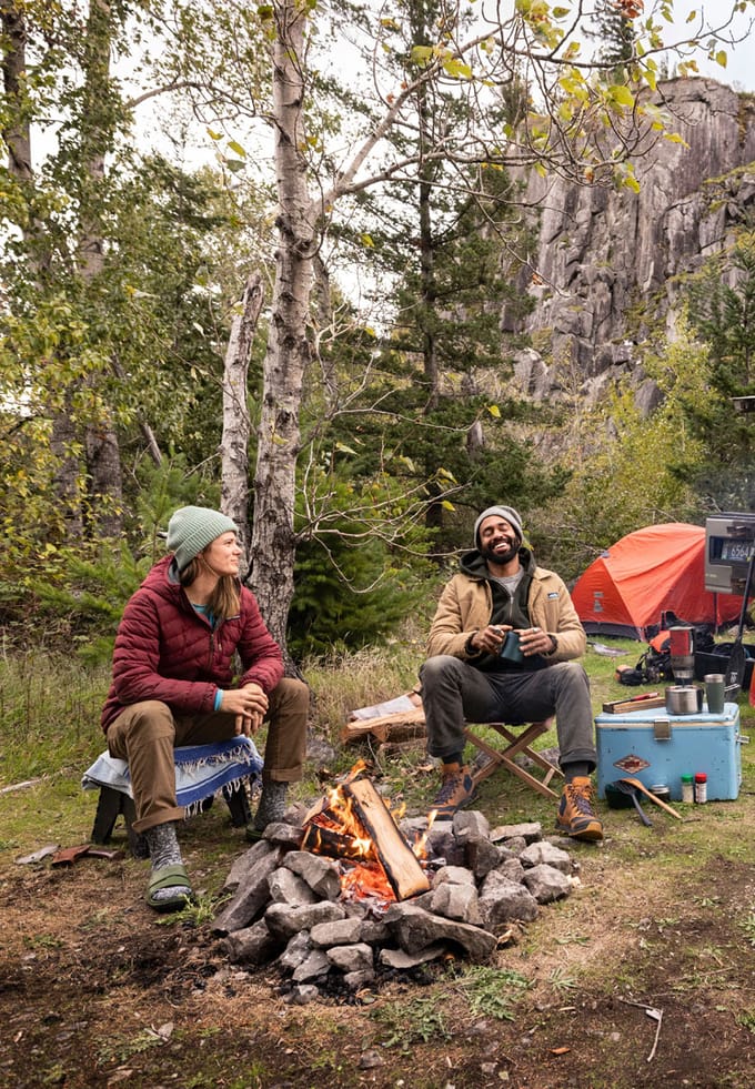 man and woman commiserating by a campfire