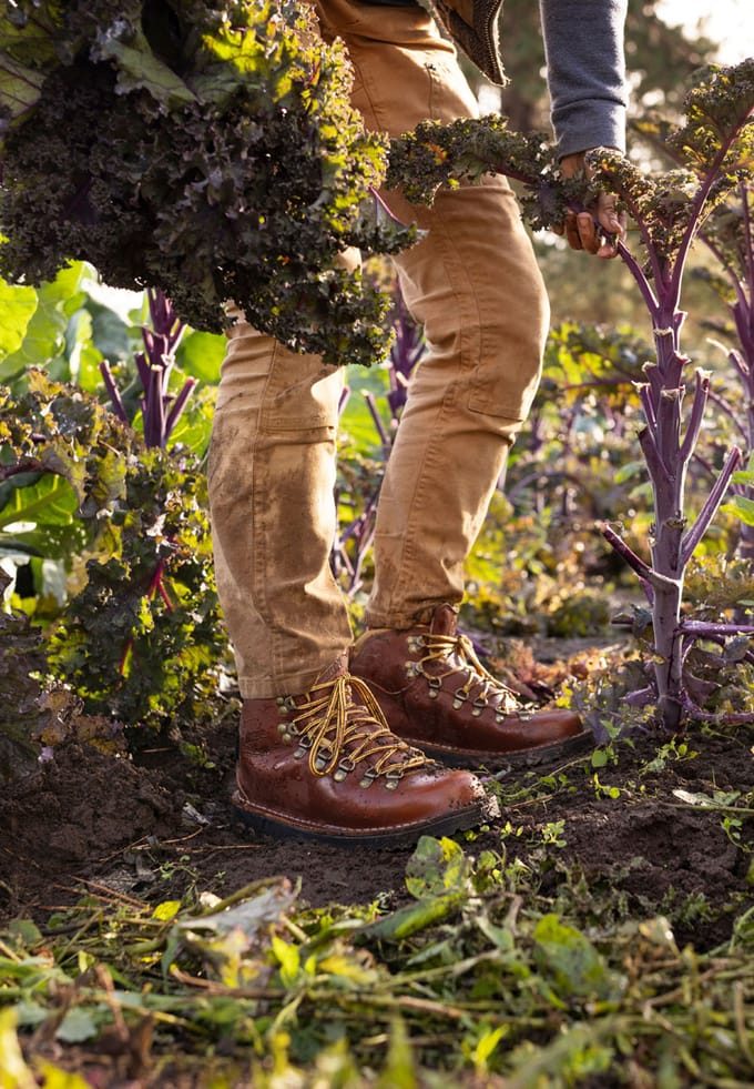 boots are seen while a woman picks leafy greens