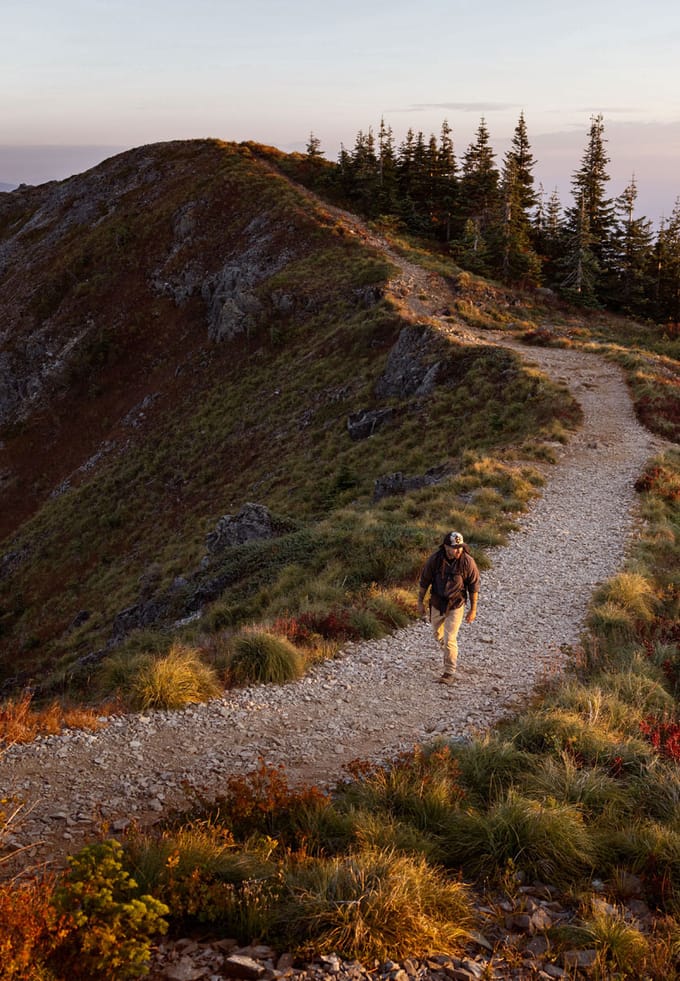 A man walks along a rocky trail in high elevation