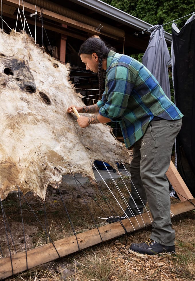 A man stretches an animal hide
