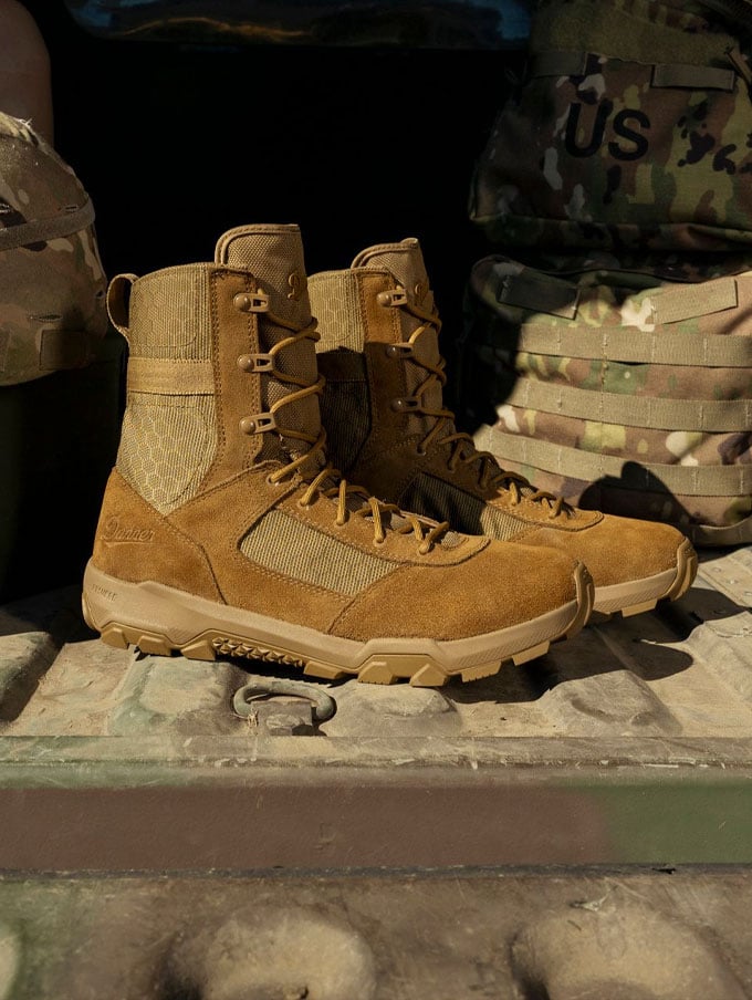 A stong-looking person suspends from a thick rope wearing camo pants, the rope is weaved around one foot showing the grippy outsole tread suggesting their boots are a key tool for their job