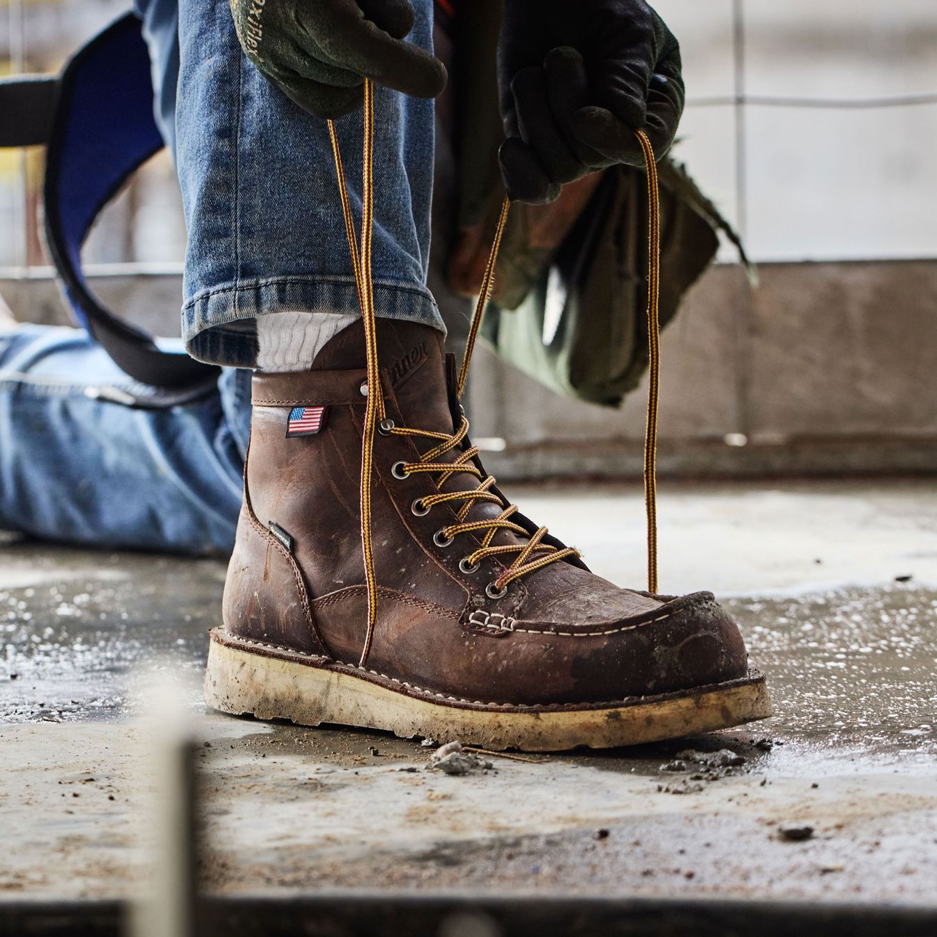 a pair of brown work boots with a moc toe being laced up
