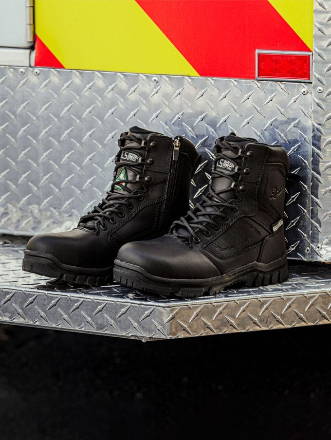 A person walks briskly up a metal staircase wearing polished black leather uniform boots and black pants