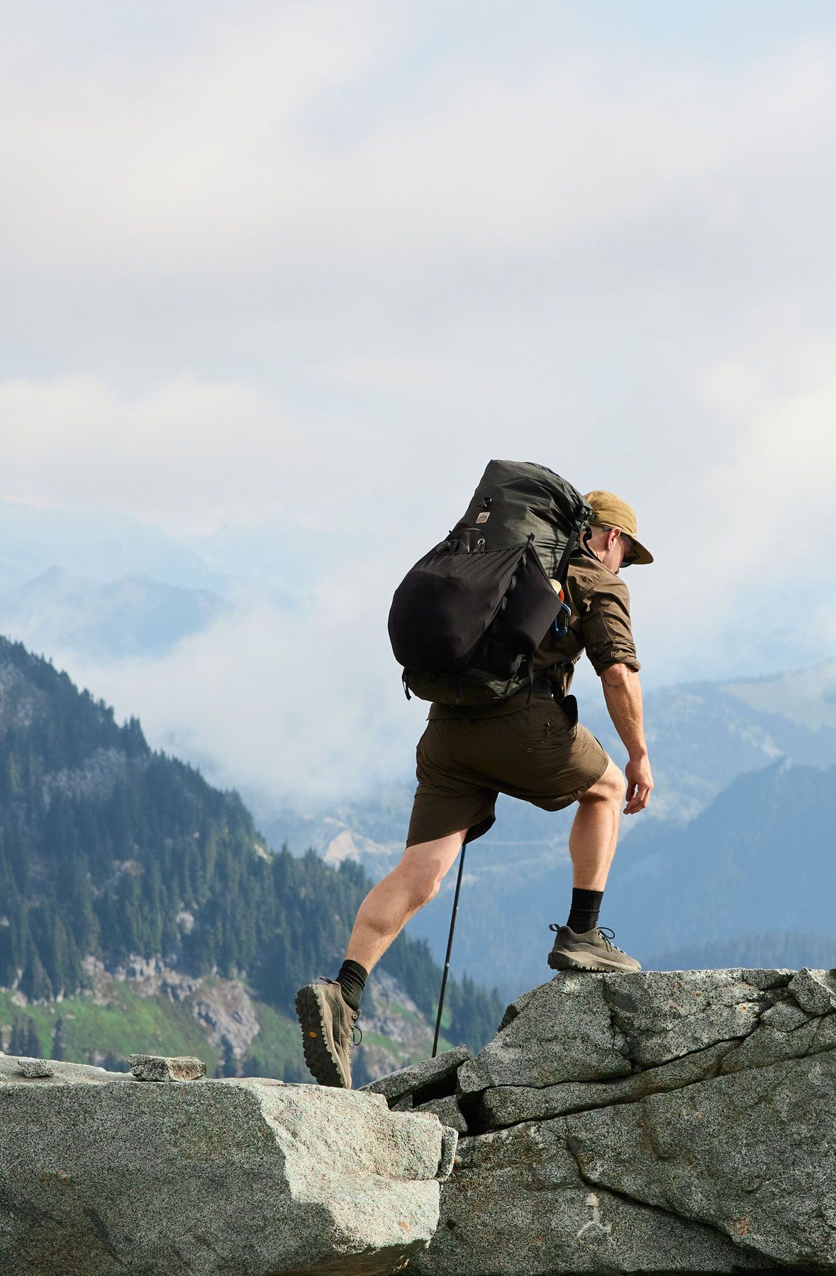 man in hiking boots ascends rocks