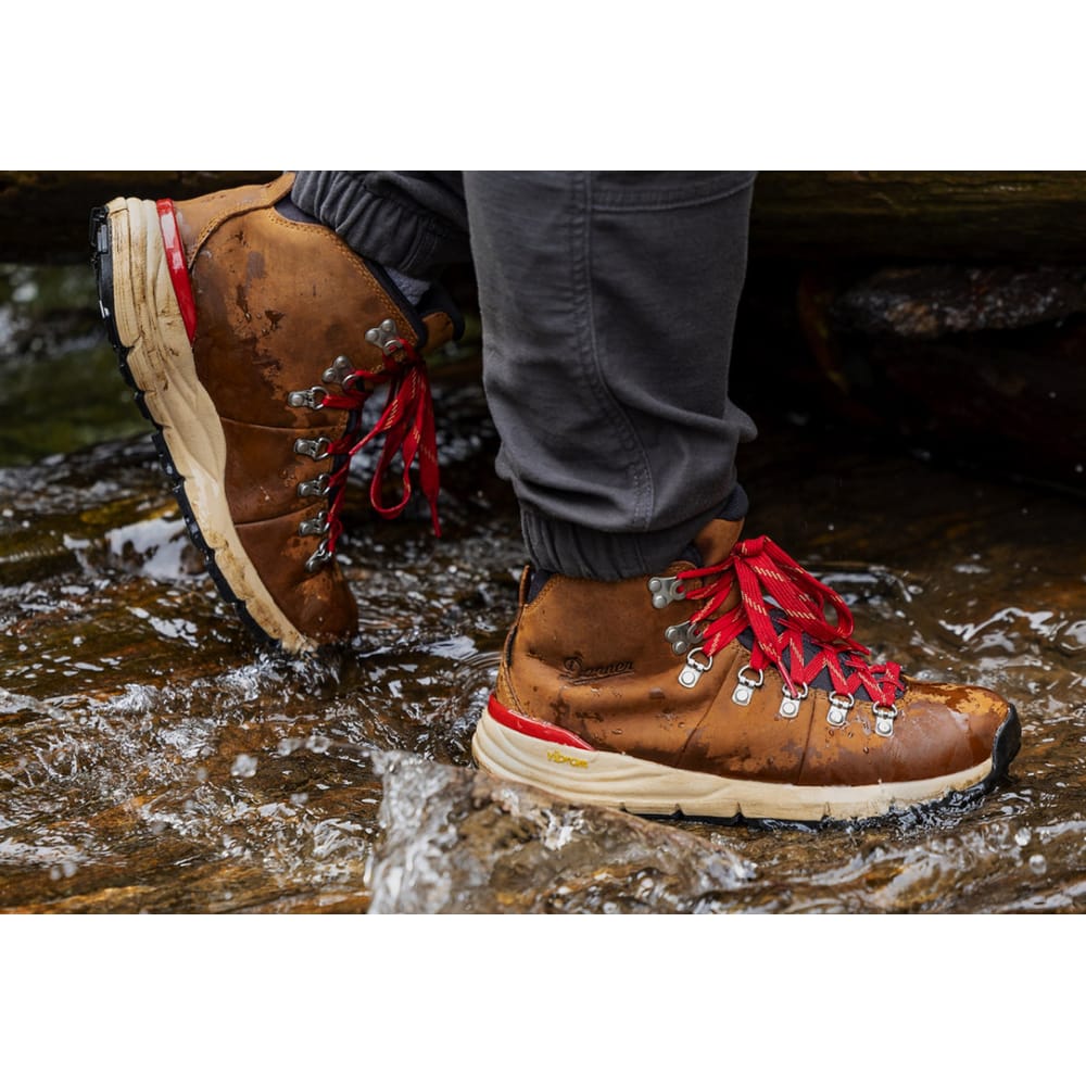 Lower body view of hiker walking on wet rocky terrain