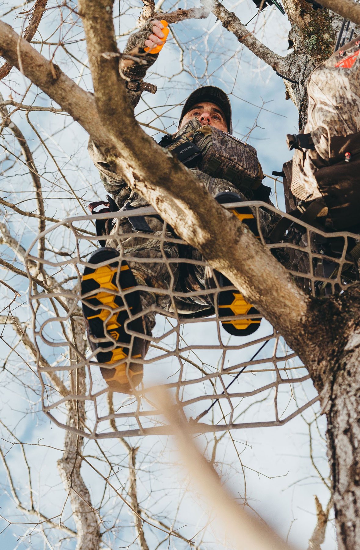 A man in gray boots ascending a tree