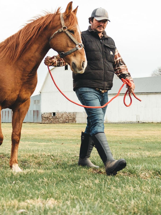 A stone colored pair of ankle high rubber boots is shown getting into a vehicle