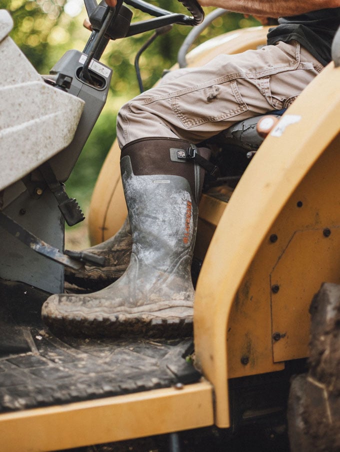A stone colored pair of ankle high rubber boots is shown getting into a vehicle