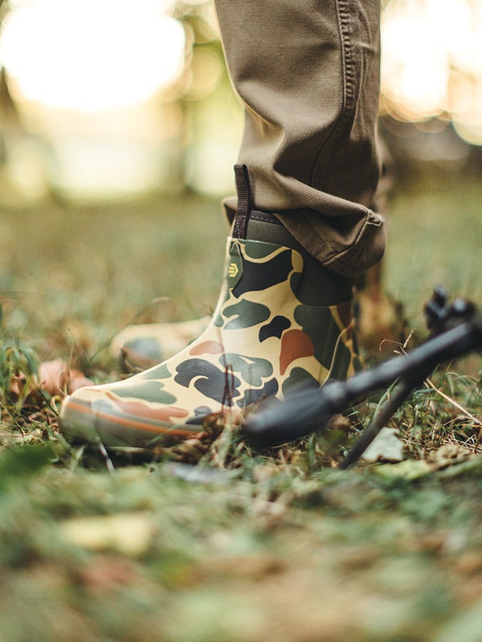 A stone colored pair of ankle high rubber boots is shown getting into a vehicle